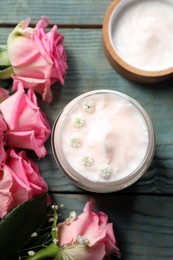 Jar of face cream and pink roses on light blue wooden table, flat lay