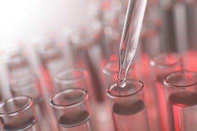 Photo of Dripping liquid from pipette into test tube on light background, closeup