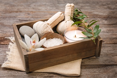 Box with spa cosmetics, accessories and orchid on wooden background