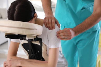 Photo of Woman receiving massage in modern chair indoors, closeup