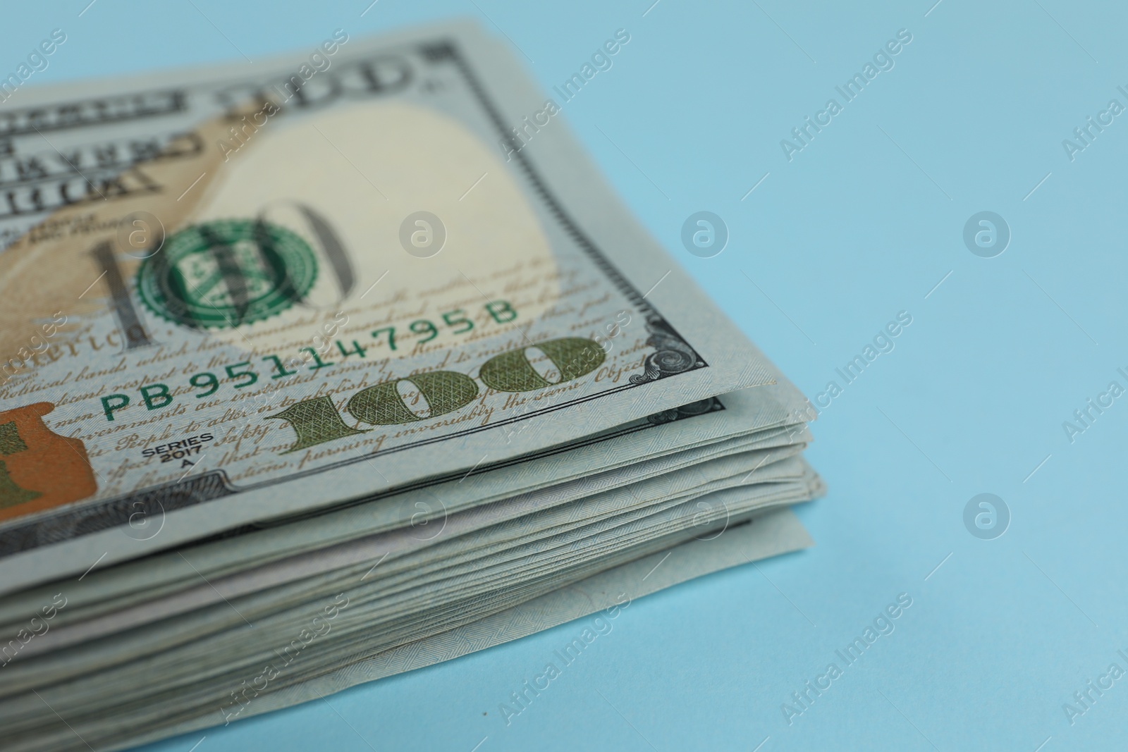 Photo of Money exchange. Dollar banknotes on light blue background, closeup