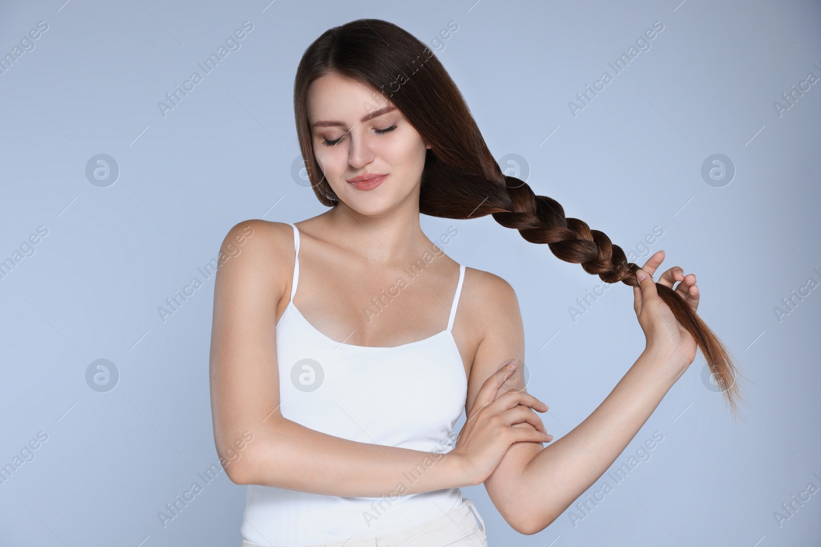 Photo of Young woman with strong healthy braided hair on light blue background