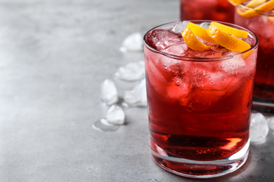 Photo of Fresh Negroni cocktail with orange zest on grey table, closeup. Space for text