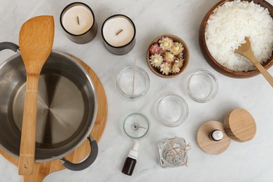 Flat lay composition with homemade candles and ingredients on white table