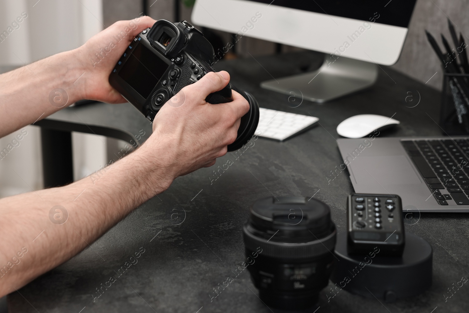 Photo of Photographer holding camera at dark table, closeup