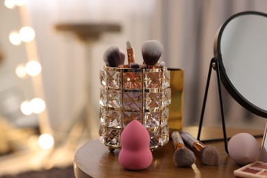 Photo of Different beauty products and mirror on wooden table in makeup room, space for text