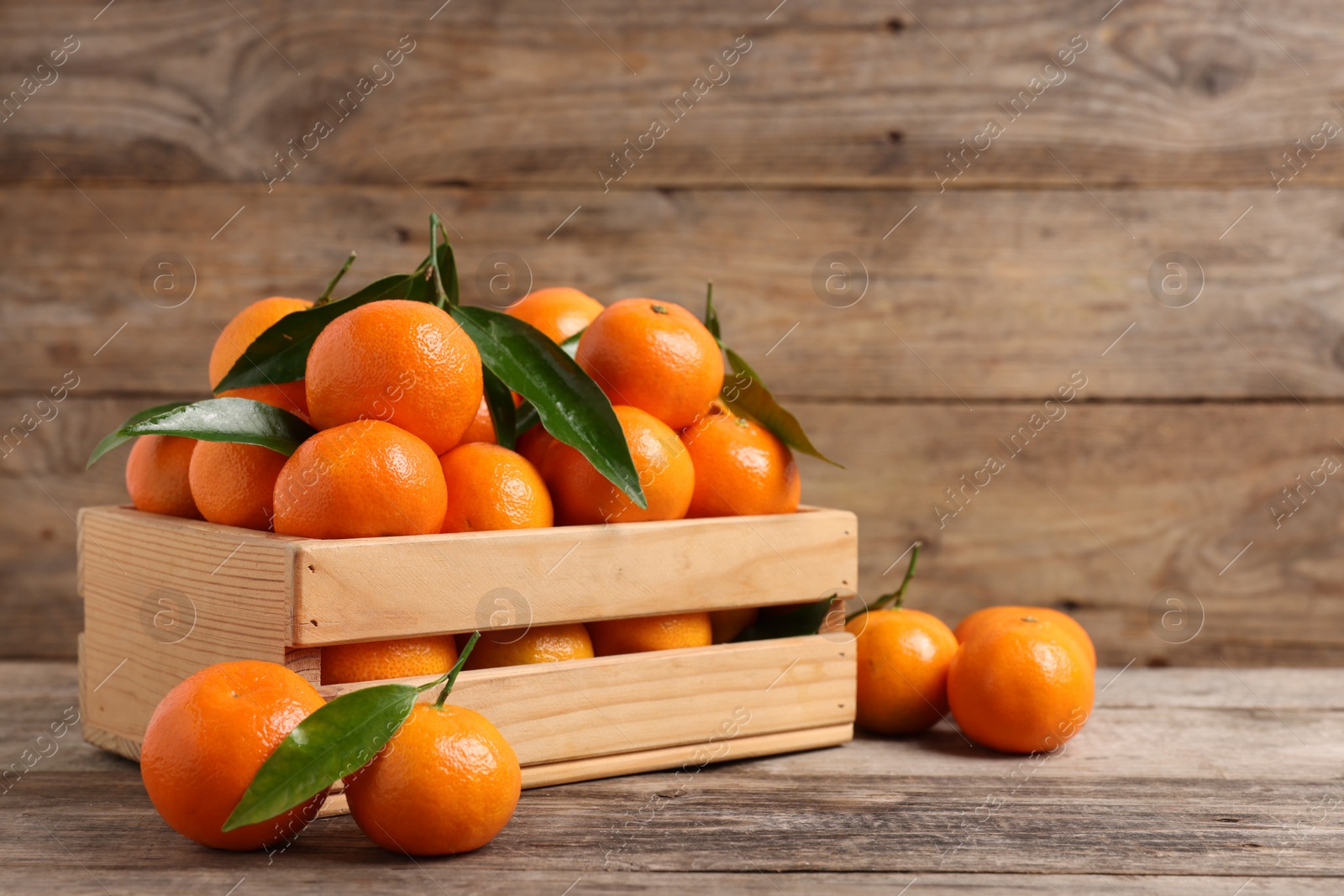 Photo of Delicious tangerines with leaves on wooden table. Space for text