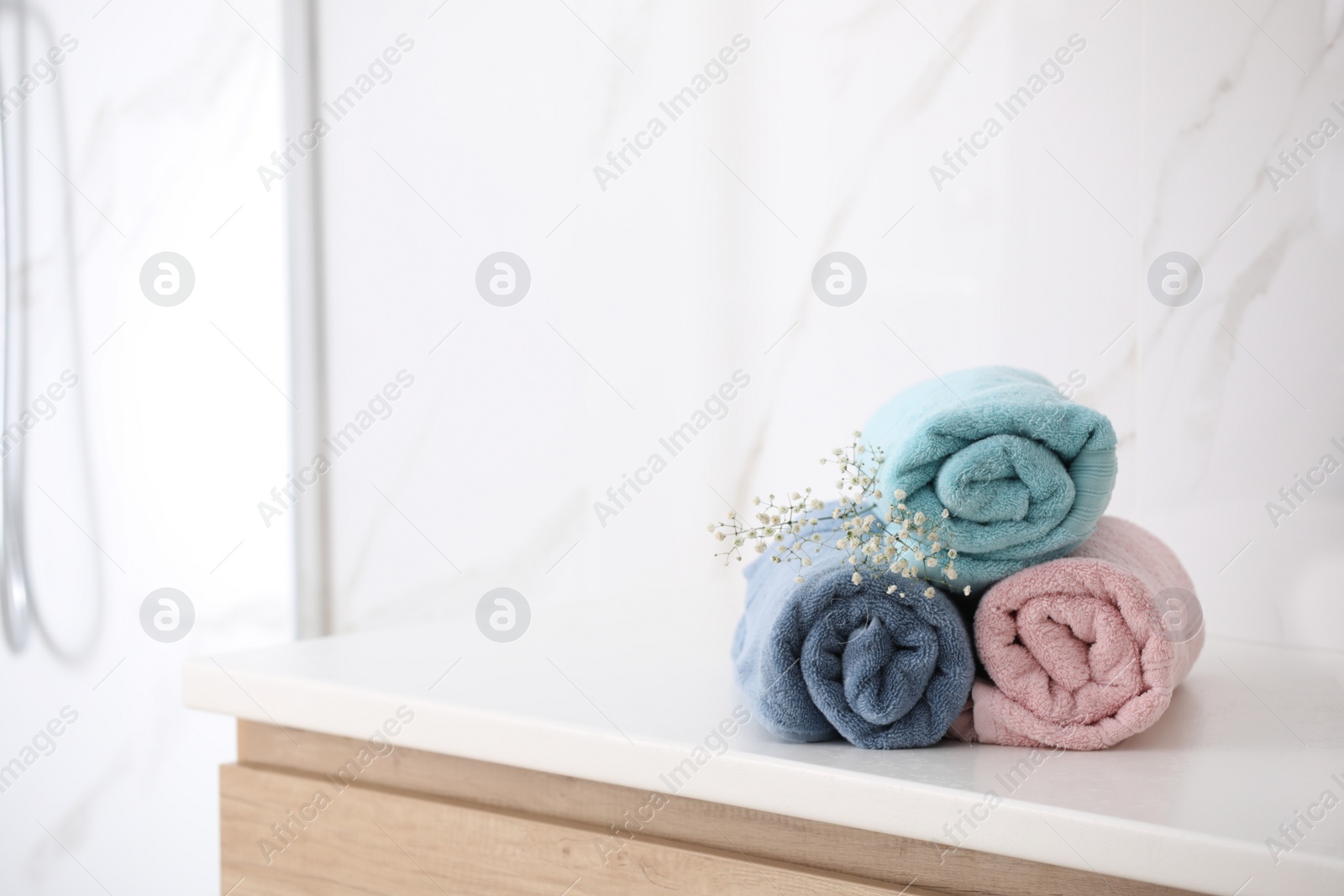 Photo of Rolled fresh towels on countertop in bathroom. Space for text