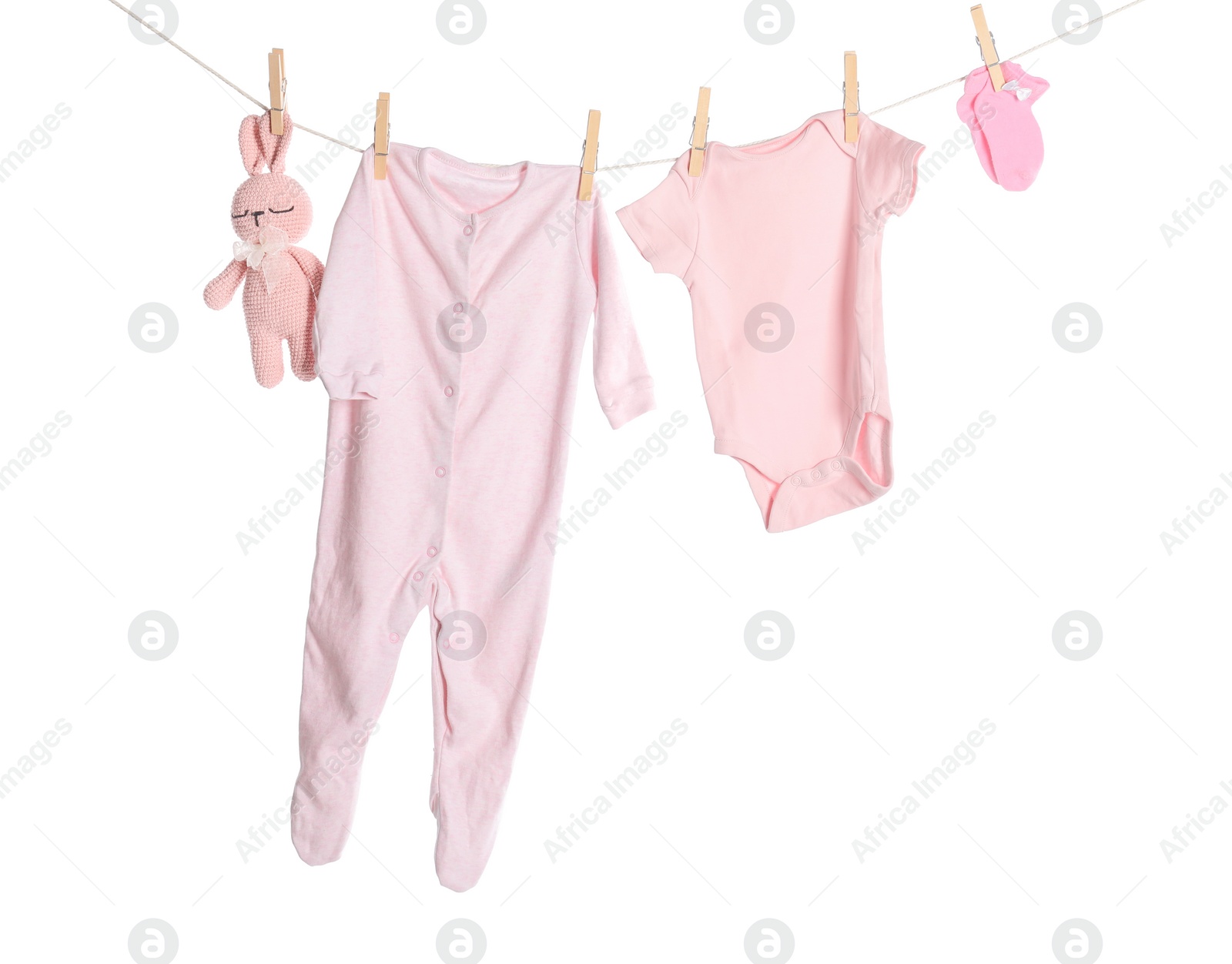 Photo of Baby clothes and toy bunny drying on laundry line against white background