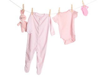 Photo of Baby clothes and toy bunny drying on laundry line against white background