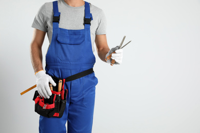 Photo of Carpenter with tool belt and chisels on light background, closeup