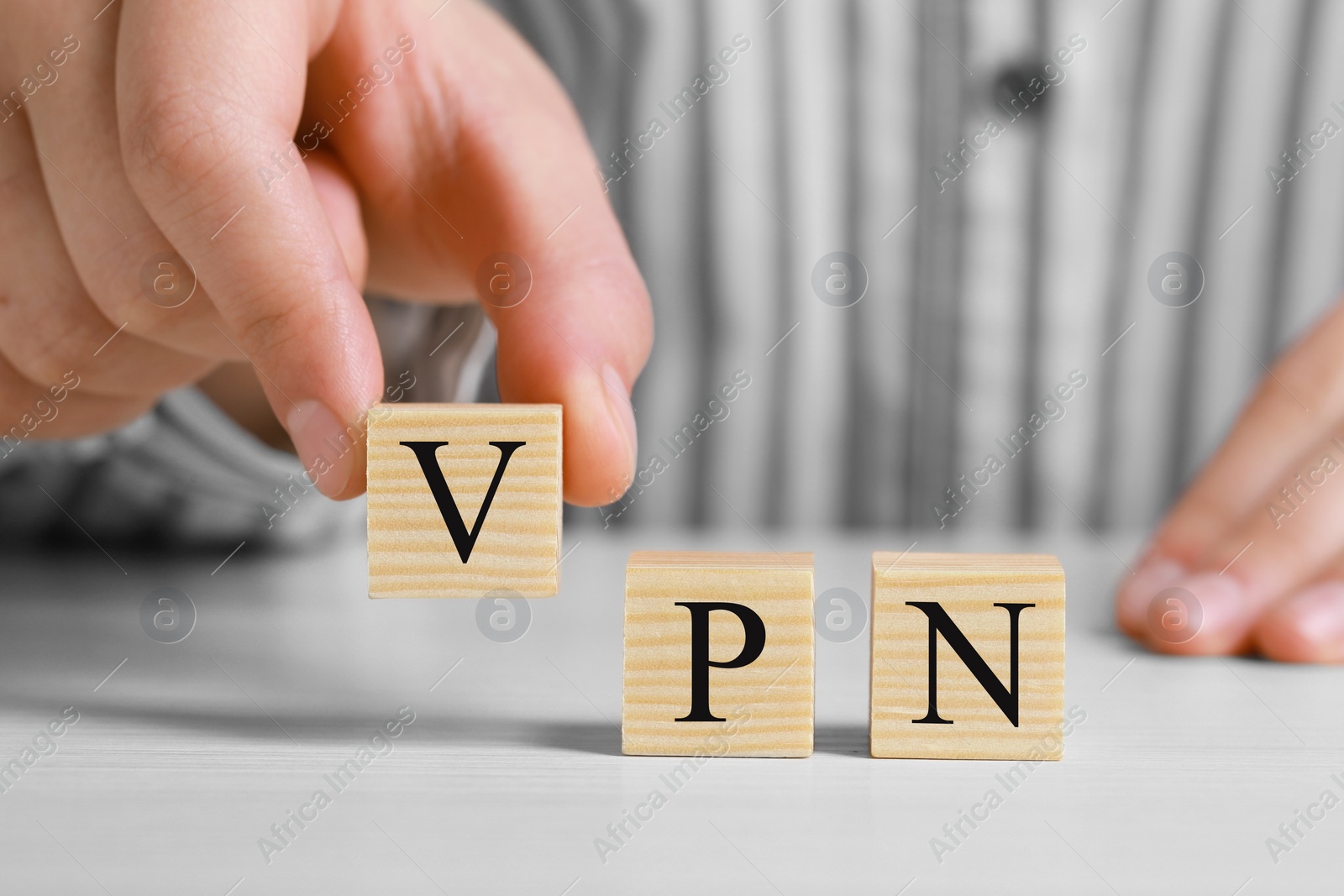 Photo of Woman making acronym VPN with cubes at wooden table, closeup