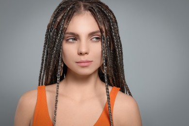 Beautiful woman with long african braids on grey background