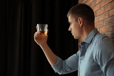 Photo of Young man with glass of whiskey indoors