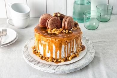 Photo of Delicious homemade cake with caramel sauce and popcorn on table