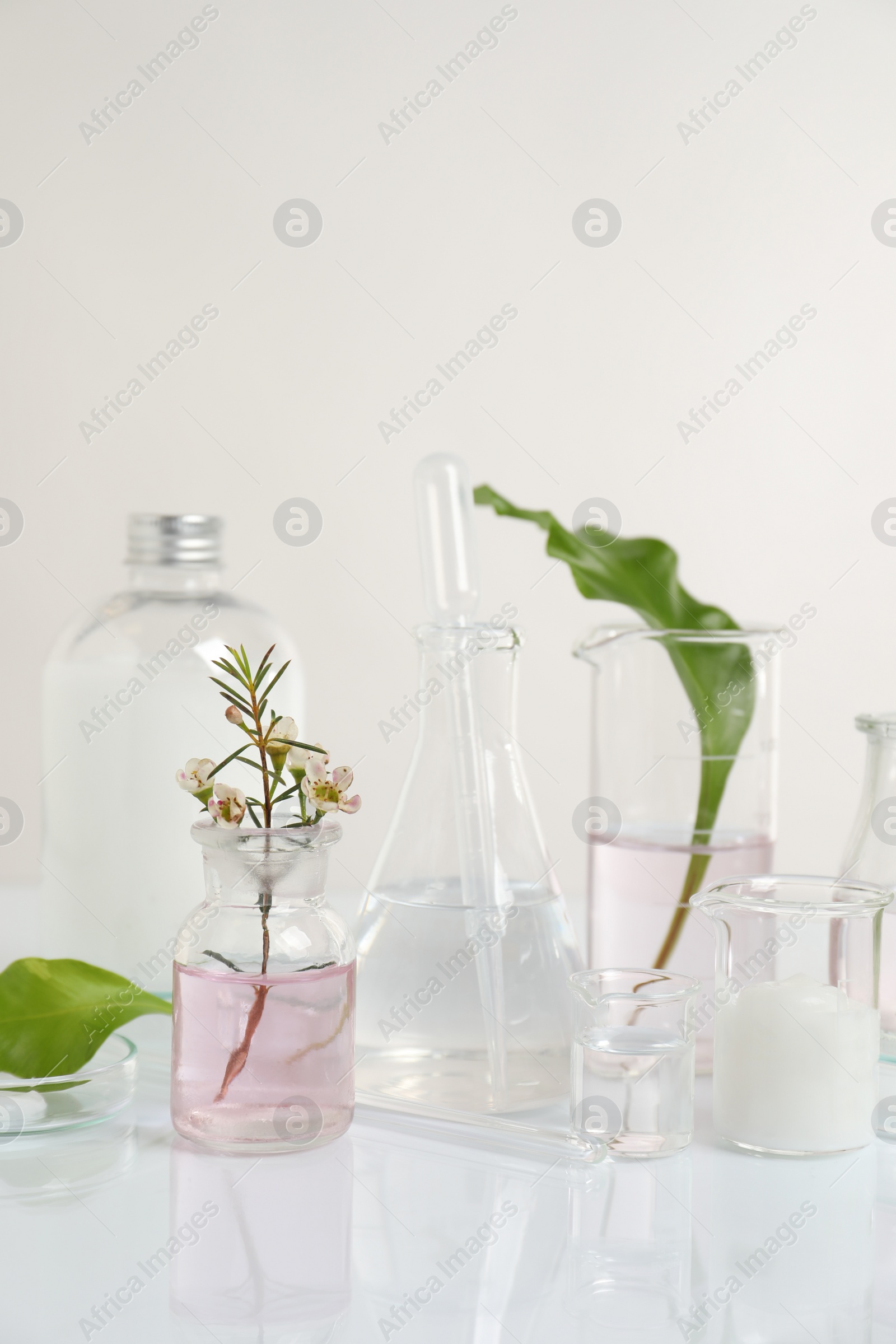 Photo of Natural ingredients and laboratory glassware for organic cosmetic product on white table