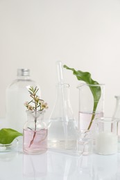 Photo of Natural ingredients and laboratory glassware for organic cosmetic product on white table