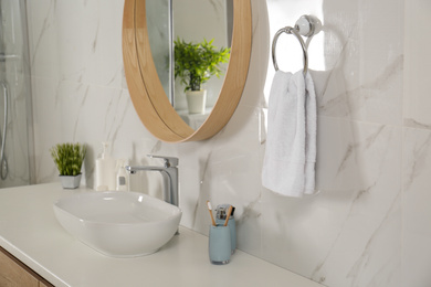 Photo of Bathroom interior with mirror, countertop and soft towel on wall