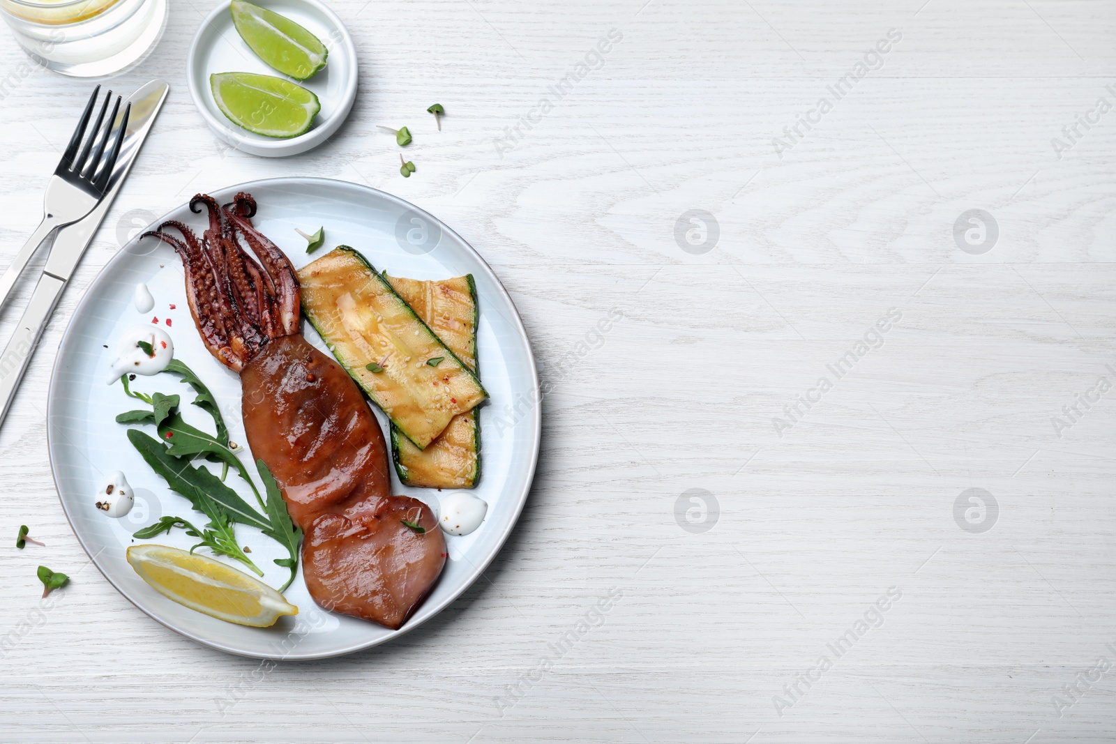 Photo of Delicious grilled squid served on white wooden table, flat lay. Space for text