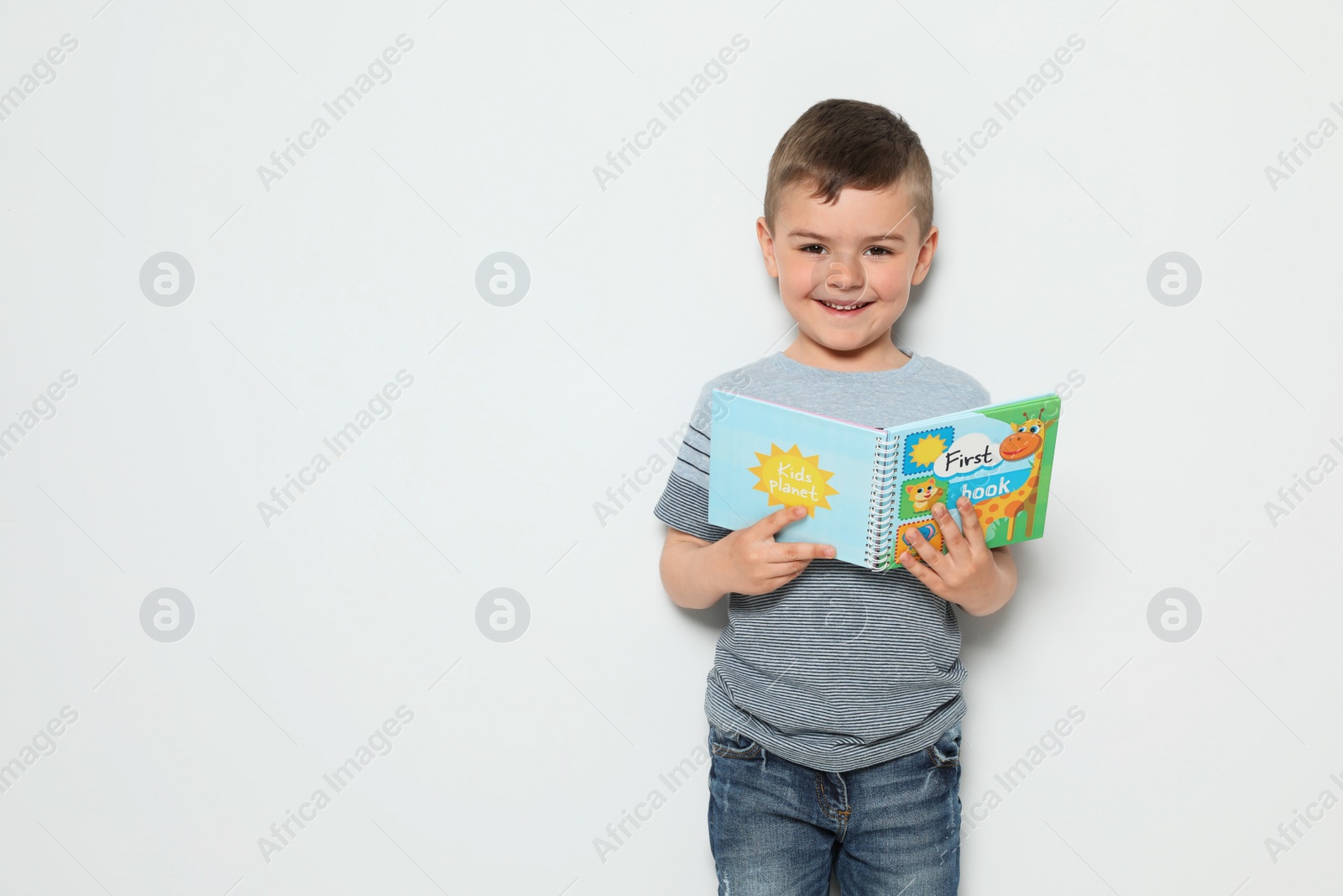 Photo of Cute little boy reading book on white background, space for text