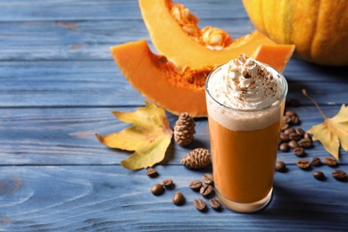Photo of Glass with tasty pumpkin spice latte on wooden table. Space for text