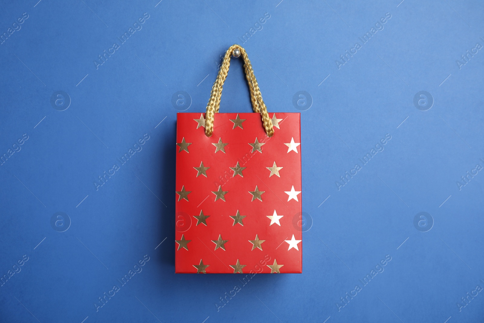 Photo of Red shopping paper bag with star pattern on blue background