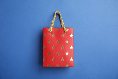 Photo of Red shopping paper bag with star pattern on blue background