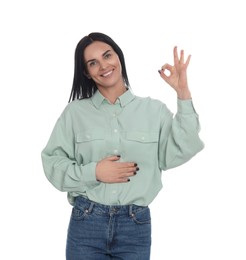Photo of Happy woman touching her belly and showing okay gesture on white background. Concept of healthy stomach