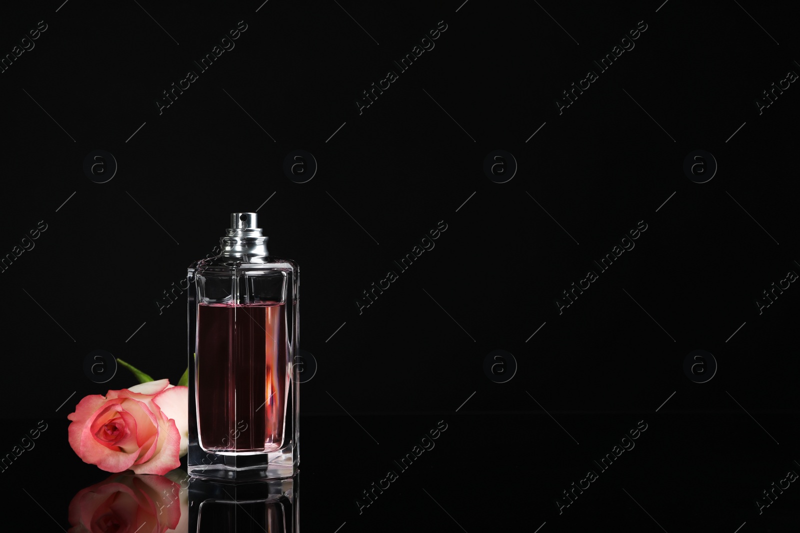 Photo of Perfume bottle and flower on black background