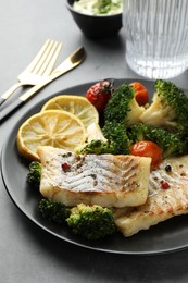 Photo of Tasty cod cooked with vegetables served on grey table, closeup