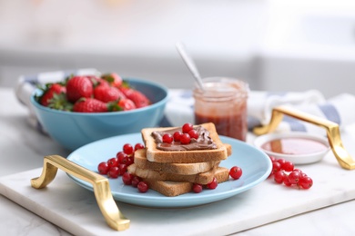 Toasted bread with chocolate spread and fresh cranberries on tray in kitchen