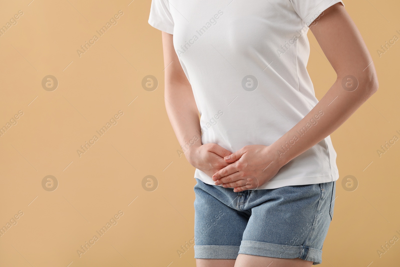 Photo of Woman suffering from cystitis on beige background, closeup. Space for text