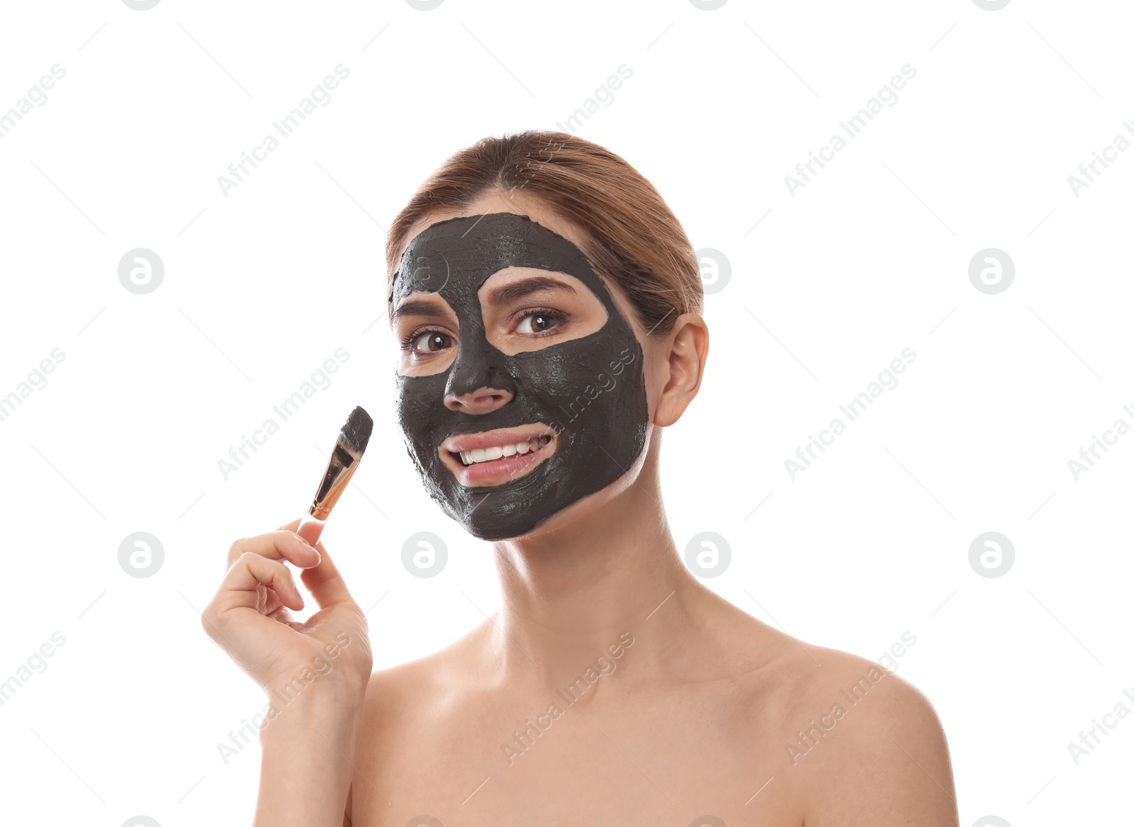 Photo of Beautiful woman applying black mask onto face against white background