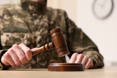 Law concept. Man in military uniform with gavel at table indoors, closeup. Space for text