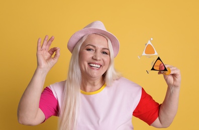 Portrait of mature woman in hipster outfit on color background