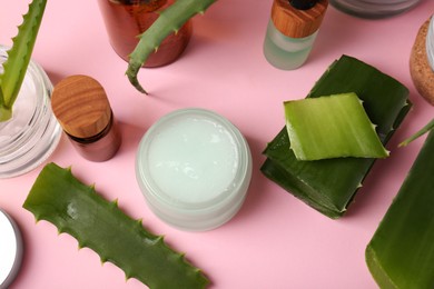 Cosmetic products and fresh aloe on pink background, above view