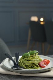 Photo of Tasty tagliatelle with spinach and tomatoes served on grey table in restaurant, closeup. Exquisite presentation of pasta dish