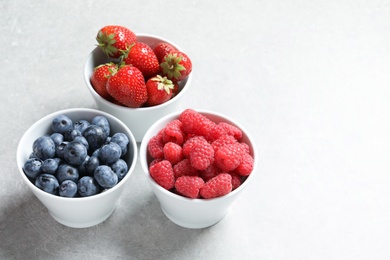 Bowls with raspberries, strawberries and blueberries on table