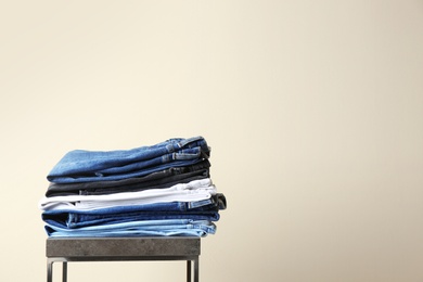 Photo of Stack of different jeans on table against color background