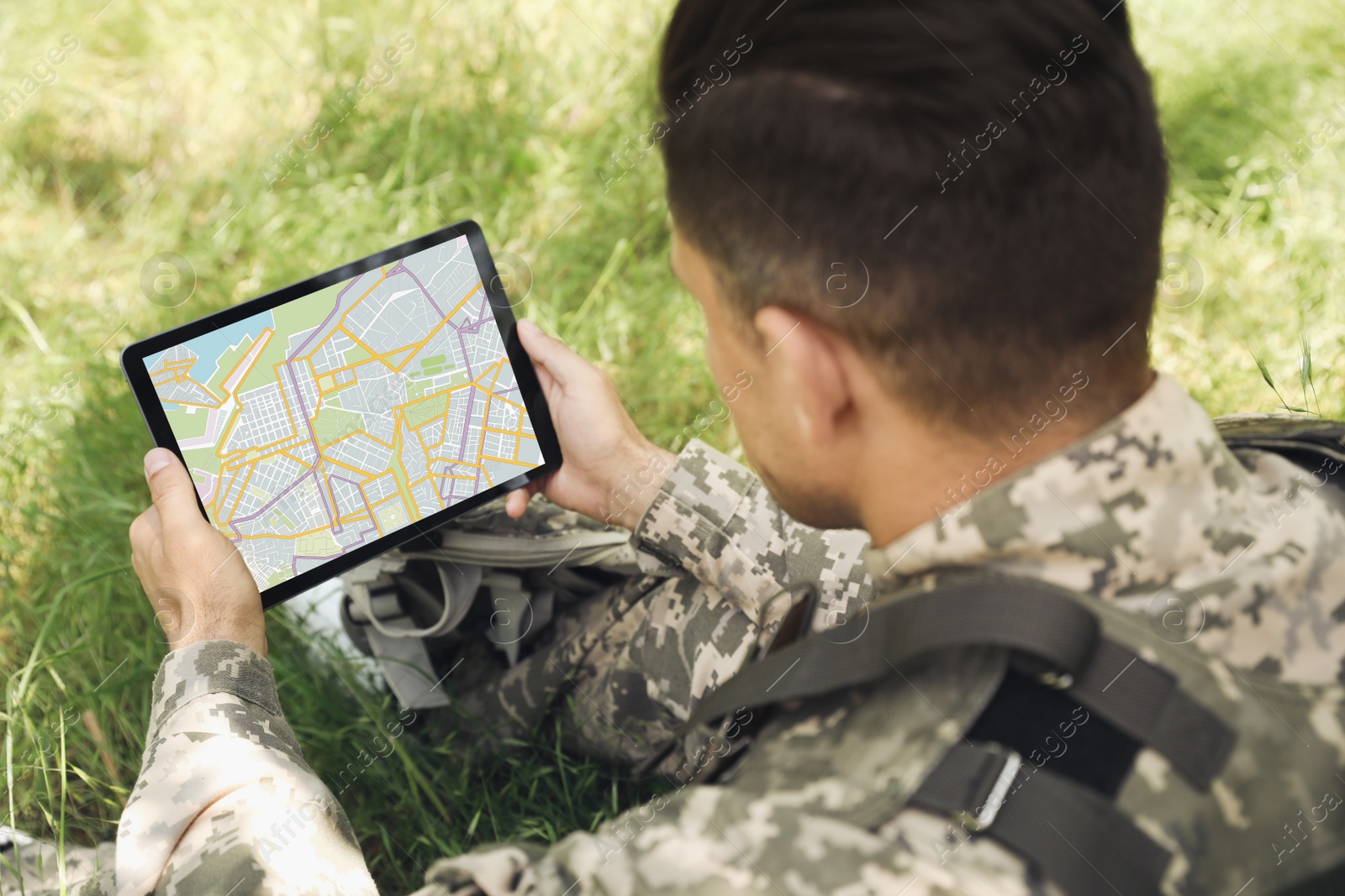 Photo of Soldier with backpack using tablet in forest