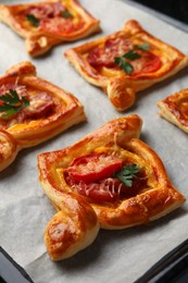 Fresh delicious puff pastry with tasty filling on baking sheet, closeup