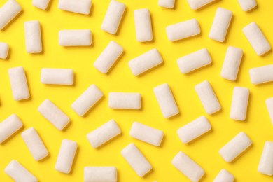 Photo of Many chewing gum pieces on yellow background, flat lay