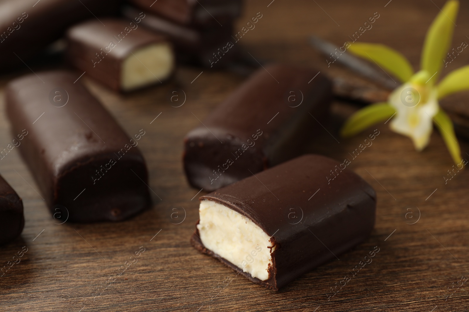 Photo of Glazed curd cheese bars on wooden table, closeup