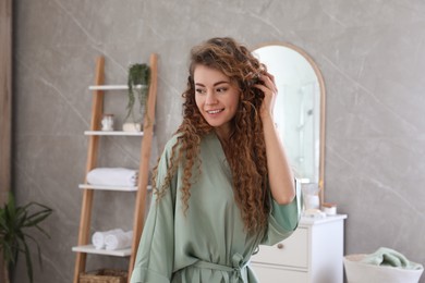 Photo of Beautiful woman wearing green silk robe in bathroom