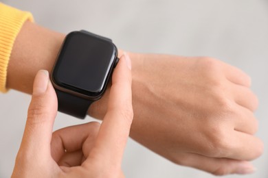 Image of Woman checking stylish smart watch on light background, closeup