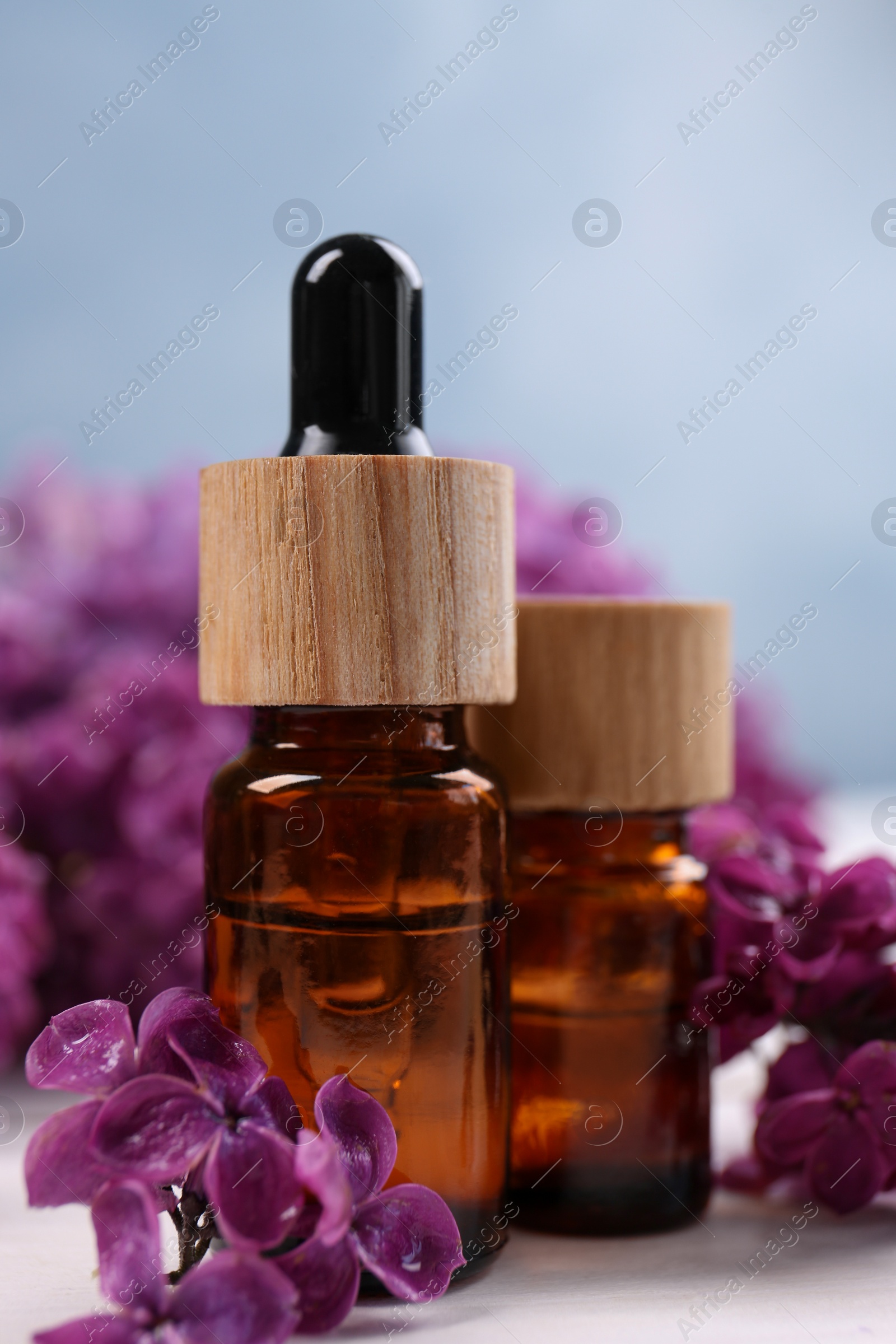 Photo of Cosmetic products and lilac flowers on white wooden table, closeup