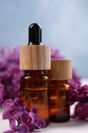 Cosmetic products and lilac flowers on white wooden table, closeup