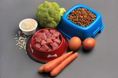 Raw meat in bowl and healthy products for pet on black background