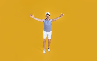 Happy sailor wearing cap on yellow background