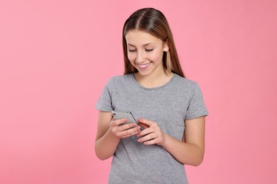 Photo of Teenage girl using smartphone on pink background